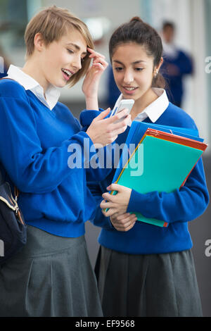 Deux étudiants femme portant des uniformes scolaires using smartphone Banque D'Images