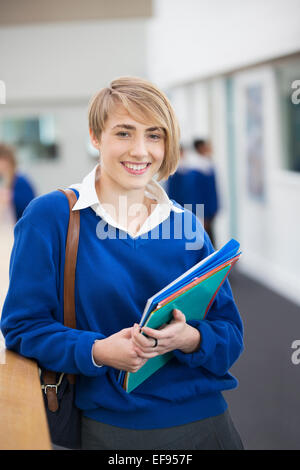 Portrait of smiling female student wearing school uniform standing in corridor Banque D'Images