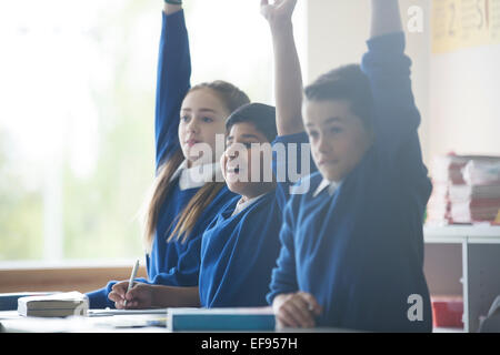 Les enfants de l'école primaire en classe raising arms Banque D'Images