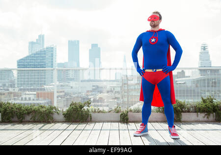 Superhero standing on city rooftop Banque D'Images