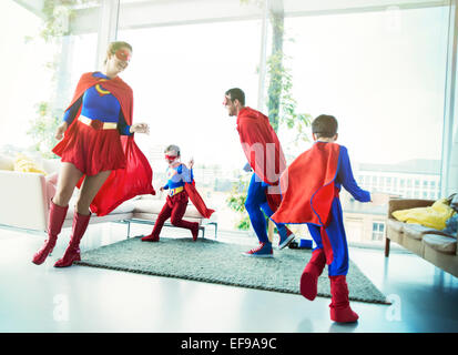 La famille de super-héros chassant les uns les autres dans la salle de séjour Banque D'Images