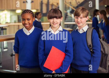 Portrait de trois enfants de l'école primaire portant des uniformes de l'école bleue dans le corridor permanent Banque D'Images
