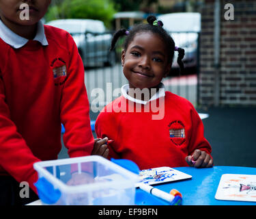 Happy smiling enfants jouant dans l'aire de jeux de l'école primaire de Londres W2 Banque D'Images