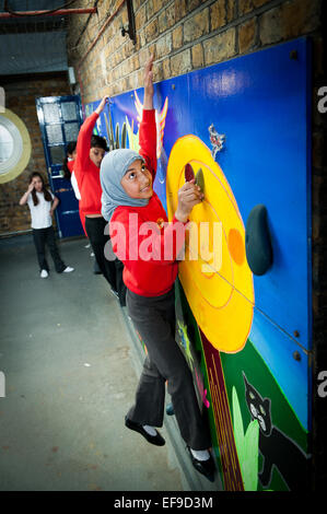 Enfants de l'école primaire escalade sur le mur d'escalade à l'école primaire Banque D'Images