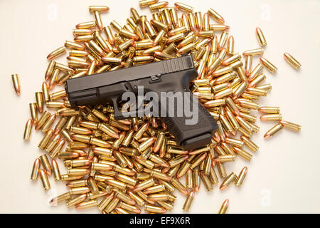 9mm pistolet Glock 19 reposant sur des tas de balles réelles sur fond blanc Banque D'Images