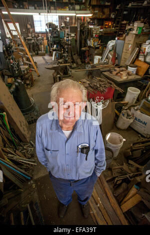 Un 82-year-old blacksmith pose fièrement dans son atelier traditionnel encombré dans le quartier de la vieille ville de Tustin, CA. Banque D'Images