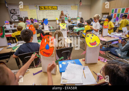 Multiracial students dans un Irvine, CA, école primaire de la classe d'écriture sont encouragés à créer des monstres de l'oeuvre de découpe à utiliser comme objet de thèmes. Remarque signer en arrière-plan. Banque D'Images