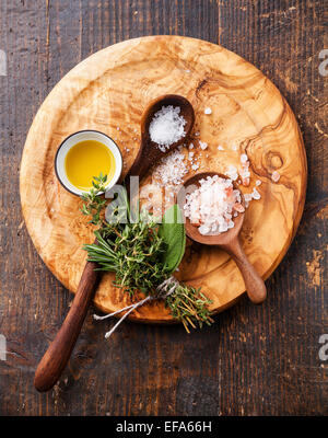 Différents types d'aliments gros sel dans des cuillères en bois sur fond sombre Banque D'Images