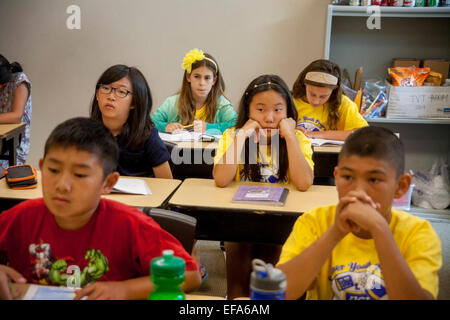 Montrant une variété d'expressions, d'Asie et du Caucase, hispanique, middle school les élèves écoutent leur professeur à un projet d'écriture en classe Irvine, CA. Remarque t shirts. Banque D'Images