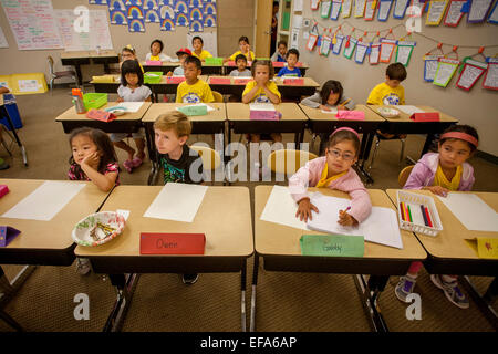 Les élèves de l'école élémentaire multiraciale montrent des degrés divers de concentration lors de l'écoute de leur enseignant dans un Irvine, CA, de classe. Essais note affichée sur mur. Banque D'Images