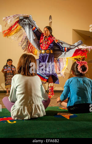 Devant un public jeune, un Indien Navajo effectue la femelle seule danse du châle portant des costumes tribaux lors d'une performance de danses amérindiennes à la Laguna Niguel, CA, public library Note jeune sœur à gauche. Banque D'Images