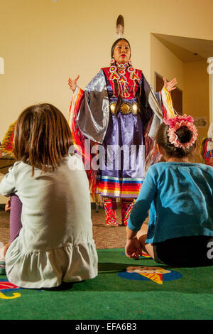 Devant un public jeune, un Indien Navajo explique la femelle seule danse du châle portant des costumes tribaux lors d'une performance de danses amérindiennes à la Laguna Niguel, CA, bibliothèque publique. Banque D'Images