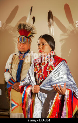 Une femme indienne Navajo explique la femelle seule danse du châle portant des costumes tribaux lors d'une performance de danses amérindiennes à la Laguna Niguel, CA, bibliothèque publique. Remarque son père en costume à gauche. Banque D'Images