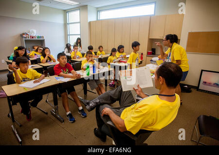 Montrant une variété d'expressions, d'Asie et du Caucase, hispanique, middle school les élèves écoutent leur enseignant la lecture à haute voix à un projet d'écriture en classe Irvine, CA. Remarque t shirts. Banque D'Images