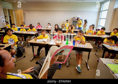 Montrant une variété d'expressions, d'Asie et du Caucase, hispanique, middle school les élèves écoutent leur enseignant la lecture à haute voix à un projet d'écriture en classe Irvine, CA. Remarque t shirts. Banque D'Images