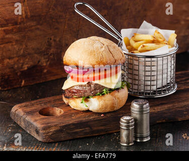 Burger à la viande et les frites dans le panier sur fond de bois Banque D'Images