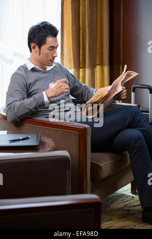 Young Woman Reading newspaper in hotel room Banque D'Images