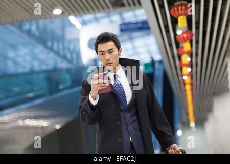 Young businessman walking in airport avec passeport et smart phone Banque D'Images