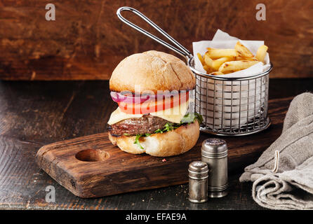 Burger à la viande et les frites dans le panier sur fond de bois Banque D'Images