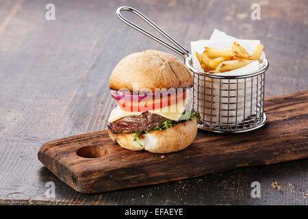 Burger à la viande et les frites dans le panier sur fond de bois Banque D'Images