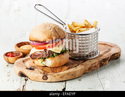 Burger à la viande et les frites dans le panier sur fond de bois Banque D'Images