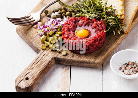 Tartare de boeuf aux câpres et l'oignon frais sur fond de bois blanc Banque D'Images