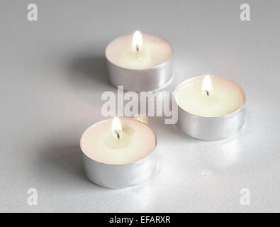 Trois blancs, allumé des bougies thé formant un triangle sur un fond blanc Banque D'Images