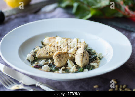 Poulet au citron avec noix de pin et de bette à carde sautées Banque D'Images