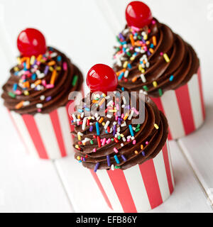 Décoré avec du glaçage au chocolat cupcakes et cerises au marasquin Banque D'Images