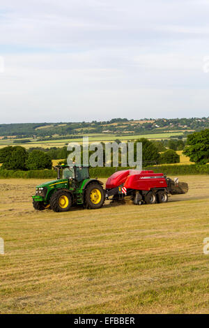 Le tracteur et la mise en balles de foin en balles de foin dans le champ, Oxfordshire, Angleterre Banque D'Images