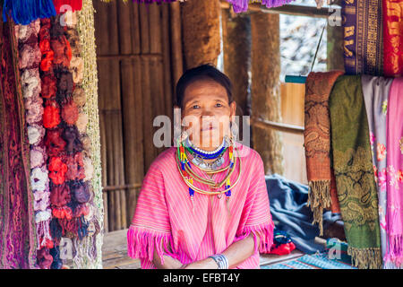 Femme avec des lobes de l'oreille percée et colliers à un étal de souvenirs dans le village Padong Karen, Chiang Rai, Thaïlande Banque D'Images
