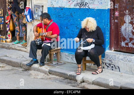 La Vieille Havane Cuba La Habana Vieja aveugle sur la mendicité supplie selles joue de la guitare musicien ambulant de la rue fille blonde handbag par magasin de souvenirs Banque D'Images