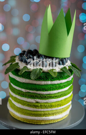 Belle éponge joyeux anniversaire avec gâteau mascarpone et raisins sur le cake stand avec couronne sur fond flou d'éclairage festif Banque D'Images