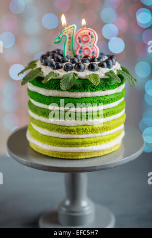 Belle éponge joyeux anniversaire avec gâteau mascarpone et raisins sur le stand de gâteau avec des bougies sur la lumière festive bokeh Banque D'Images