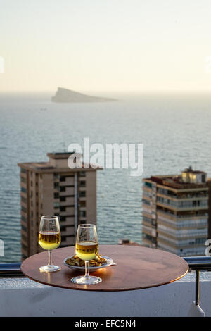Verres de vin blanc avec des collations au bar sur le toit et vue sur l'île de paon, Benidorm, Costa Blanca, Espagne Banque D'Images