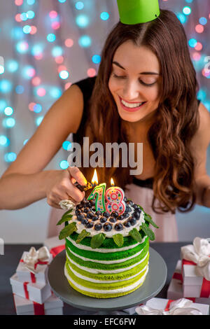 Dix-huit fille avec happy birthday cake bougies d'éclairage festif sur fond clair Banque D'Images