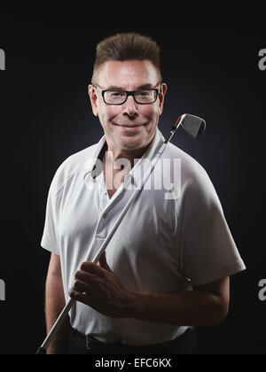 Homme mature golfer portant une chemise blanche et il est titulaire d'un club de golf de fer sur son épaule et il looking at camera - studio shot, bl Banque D'Images