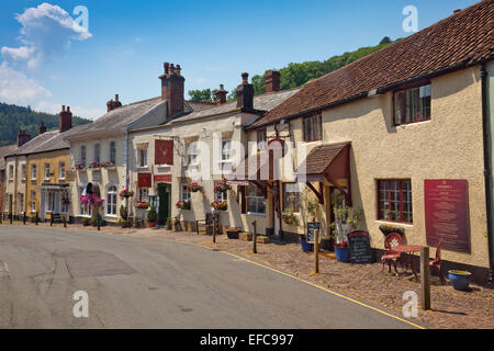 Un mélange de pubs et restaurants et les chaussées pavées dans West Street, Dunster, Somerset, England, UK Banque D'Images