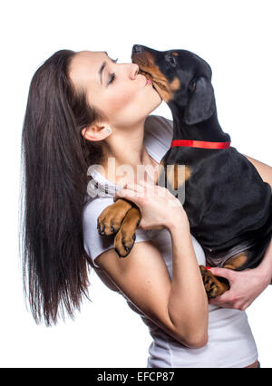 Brunette girl kissing her dobermann chiot isolé sur fond blanc Banque D'Images