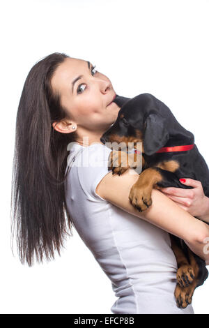 Brunette girl kissing her dobermann chiot isolé sur fond blanc Banque D'Images