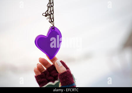 Femme de mitaines pour atteindre le purple heart against a white background bokeh Banque D'Images