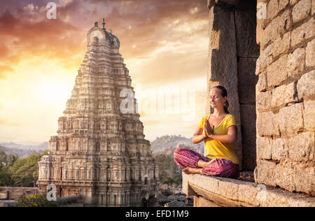 Femme avec Namaste mudra assis près de temple Virupaksha à Hampi, Karnataka, Inde Banque D'Images