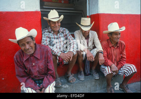 Un groupe d'hommes en vêtements traditionnels restent assis dans une des rues de Chichicastenango Banque D'Images