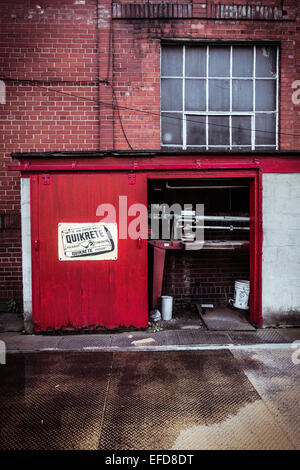 L'échelle industrielle se trouve dans un petit bâtiment rouge à côté d'un bâtiment en briques rouges. Banque D'Images