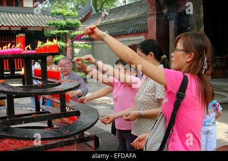 Chengdu, Chine : les femmes d'encens d'éclairage d'un brasero de brûler des bougies rouges dans une cour de la temple Wenshu Banque D'Images