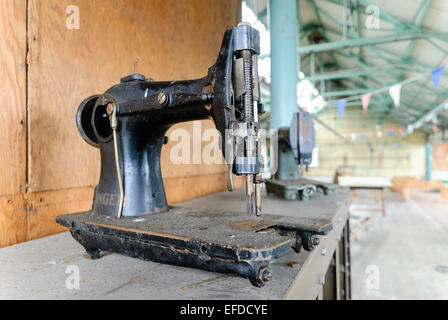 Une très vieille Singer à entraînement mécanique de machines à coudre industrielle dans une usine abandonnée. Banque D'Images