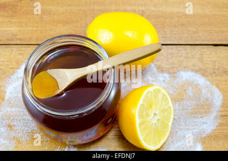 Pot de miel foncé et d'une cuillère de bois et les citrons sur une table Banque D'Images