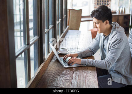 Young man using laptop in cafe Banque D'Images