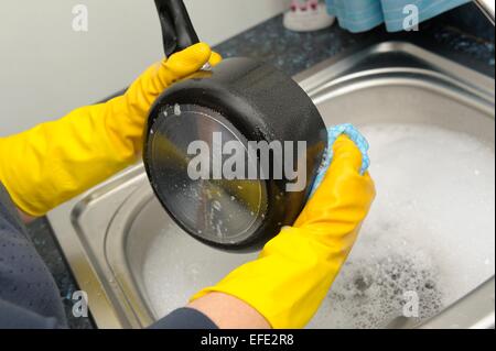 Une femme lave-pots portant des gants de caoutchouc jaune Banque D'Images