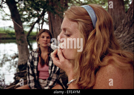 Deux adolescentes fumer lors d'une sortie dans les bois de cèdre en mai 1973 Leakey, Texas. Banque D'Images